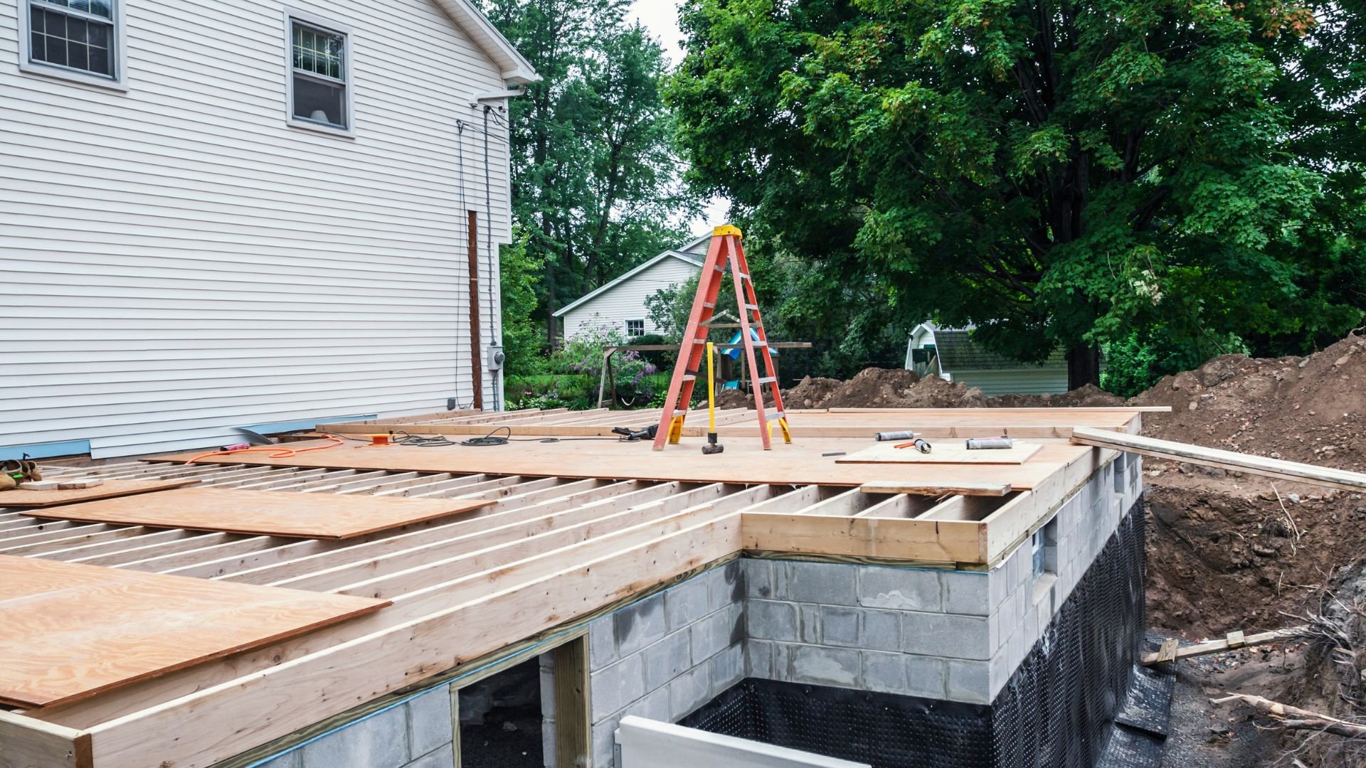Home construction site with wooden deck framing and orange ladder