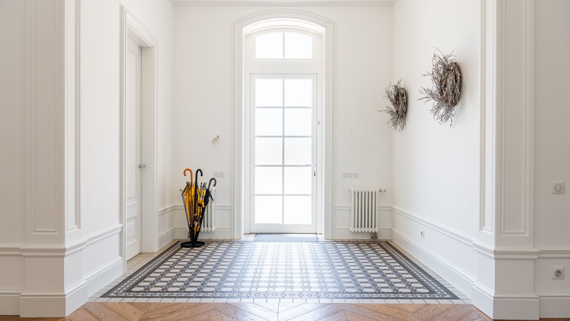 Bright entryway with arched window, patterned tiles, and yellow umbrellas