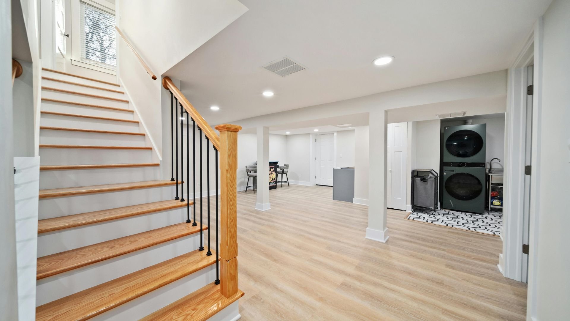 Modern finished basement with wooden stairs and laundry area