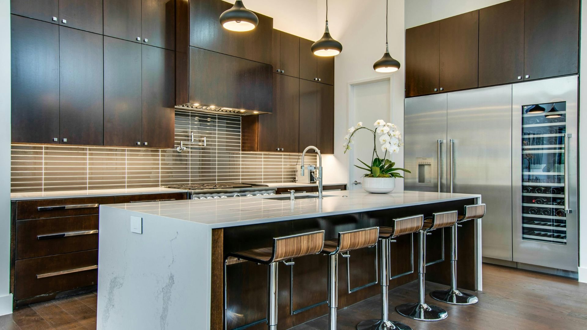 Modern kitchen with dark cabinets, white countertop, and bar stools