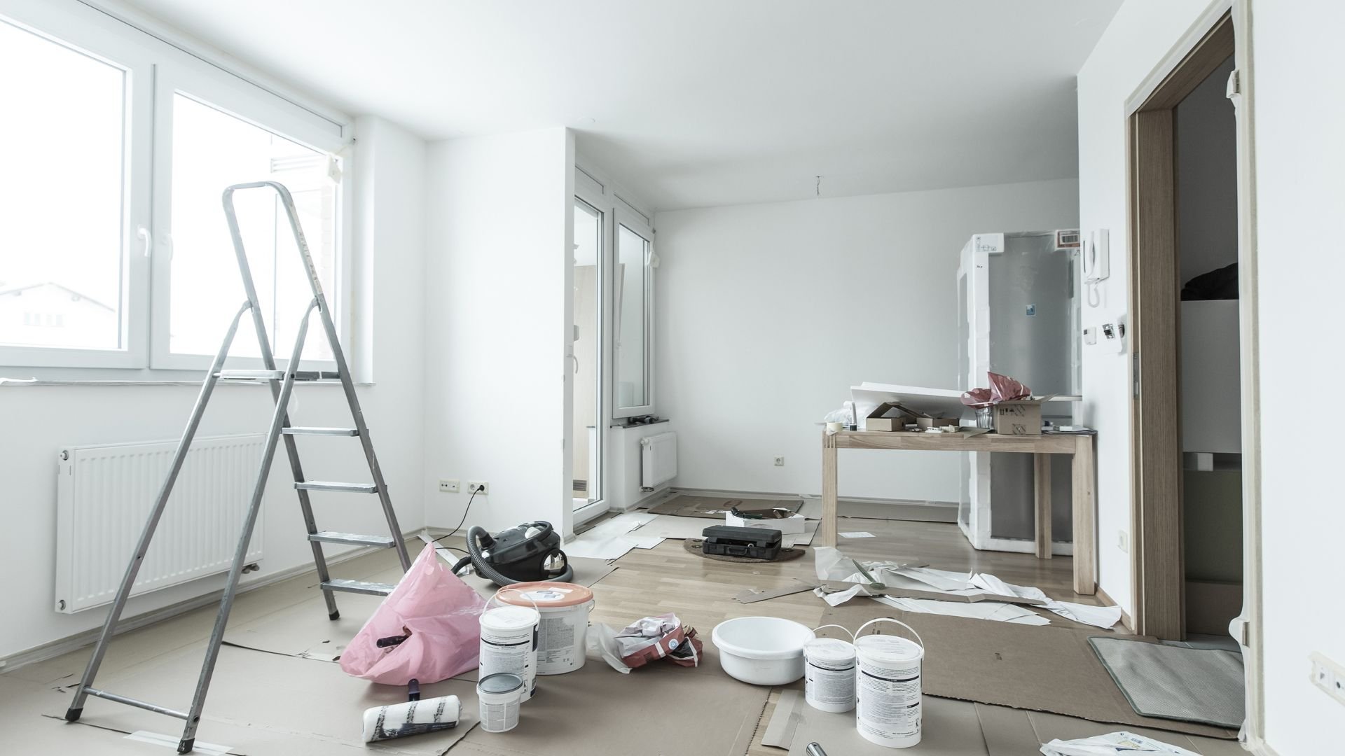 Room under renovation with painting supplies, ladder, and scattered materials