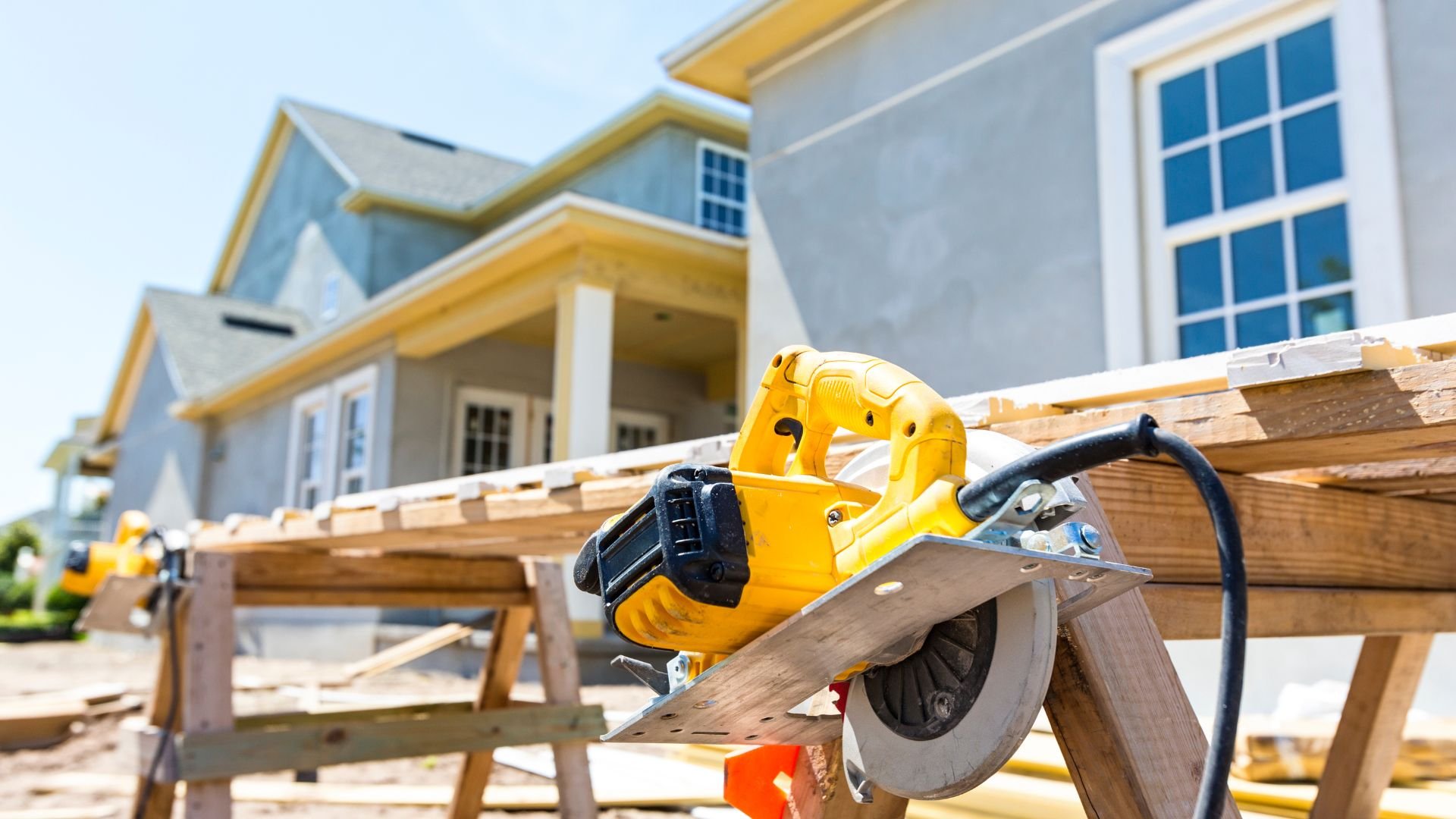 Yellow circular saw on wooden planks during house construction project