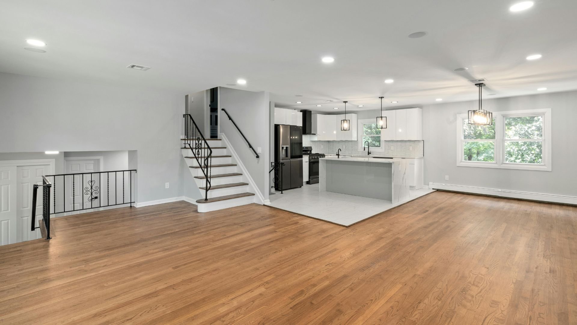 Modern open-concept kitchen and living area with wooden floors and stairs
