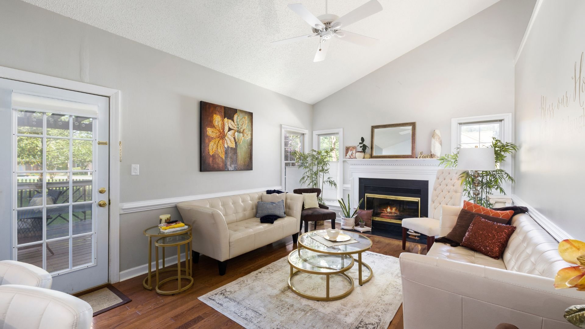 Cozy living room with fireplace, white sofas, gold tables, and floral artwork