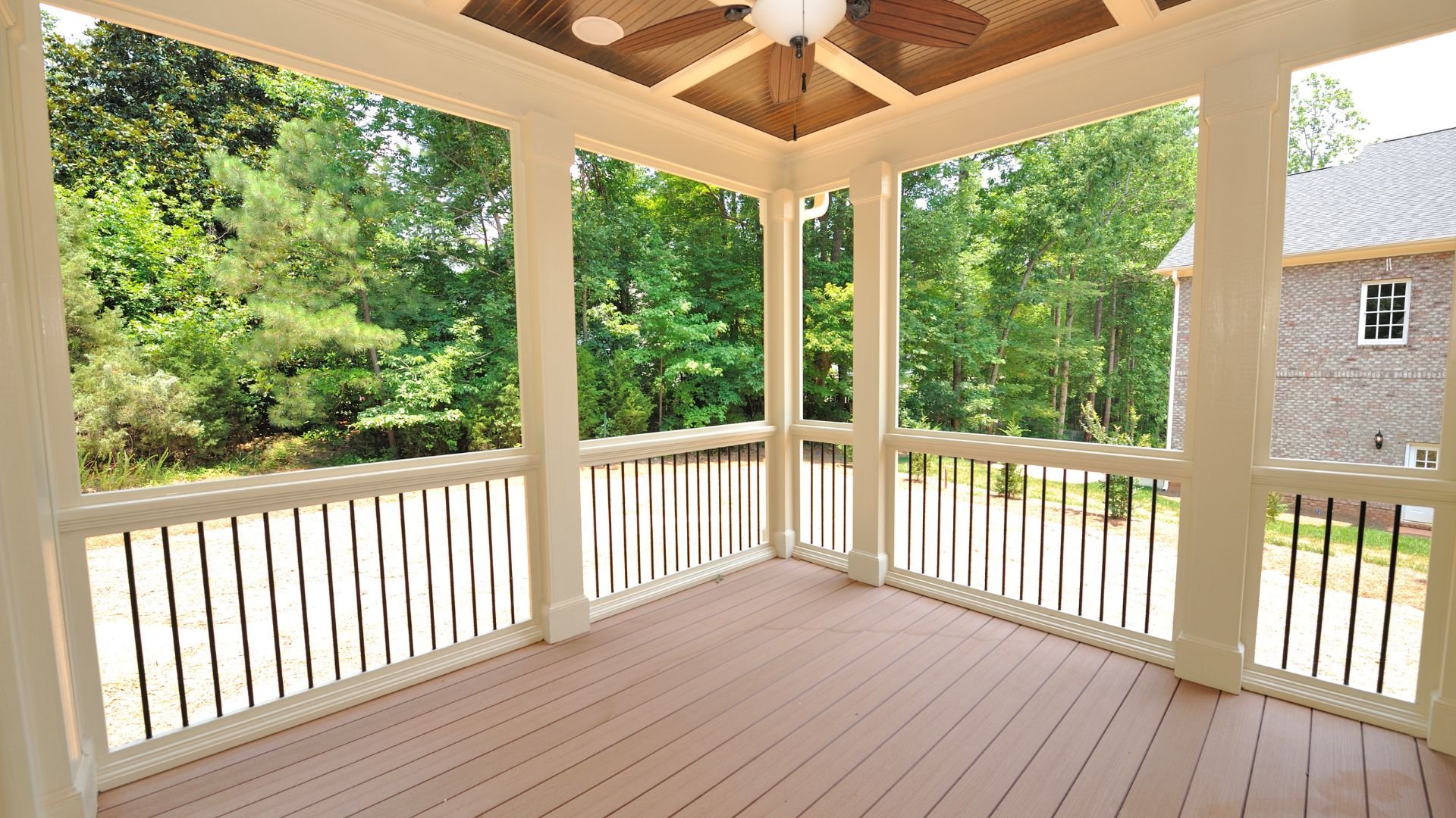 Spacious covered porch with wooden floor overlooking lush green forest